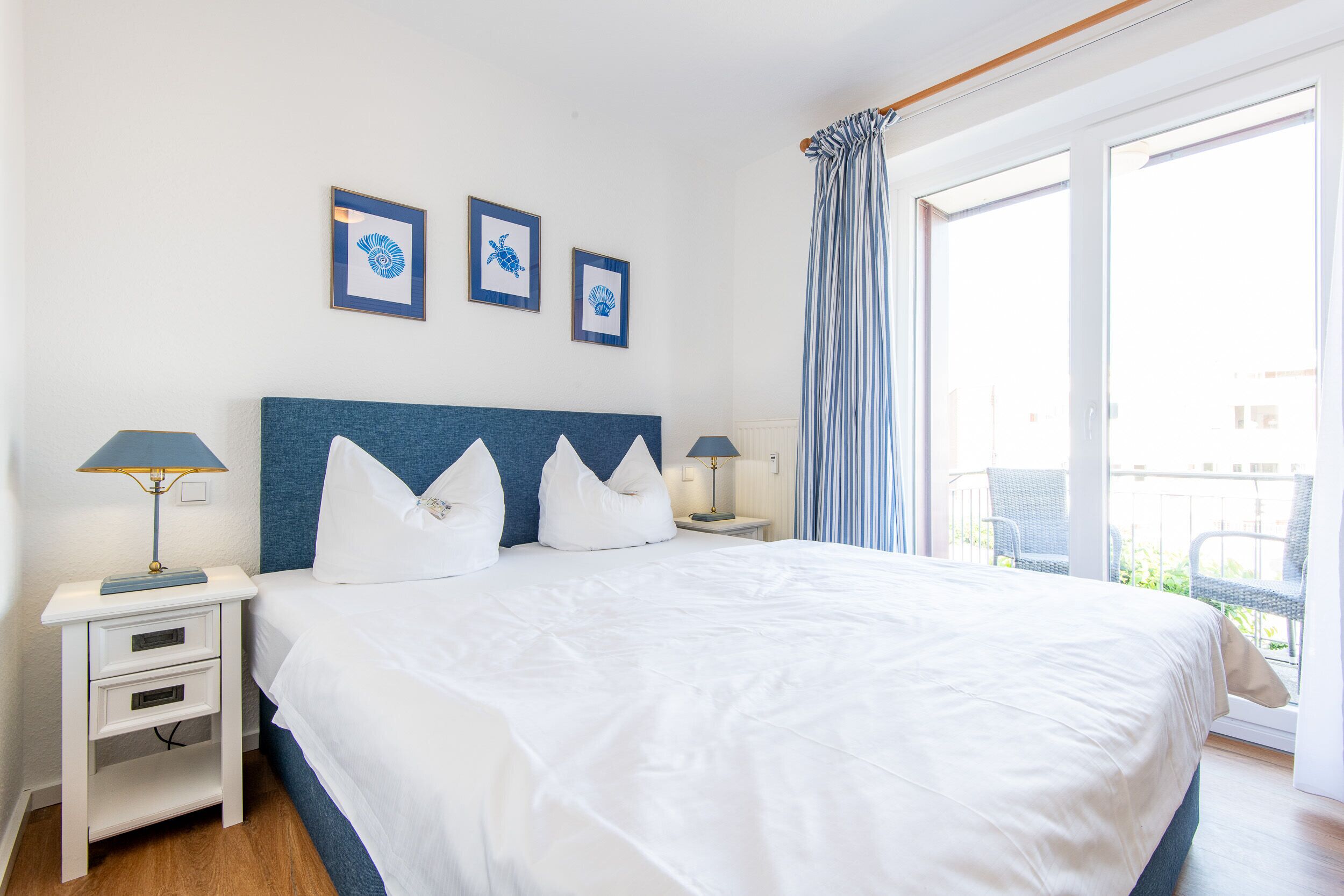 A bedroom with a large bed, two bedside tables, and a view of the outside through a sliding glass door.