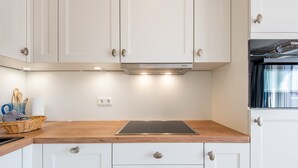 Eine moderne Küche mit weißen Schränken, einer Holz Arbeitsplatte und einem eingebauten Herd.