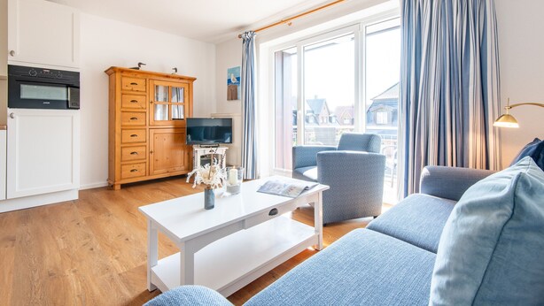 Ein modernes Wohnzimmer mit einem weißen Couchtisch, einem blauen Sofa und einer Holzkommode mit Flachbildfernseher.