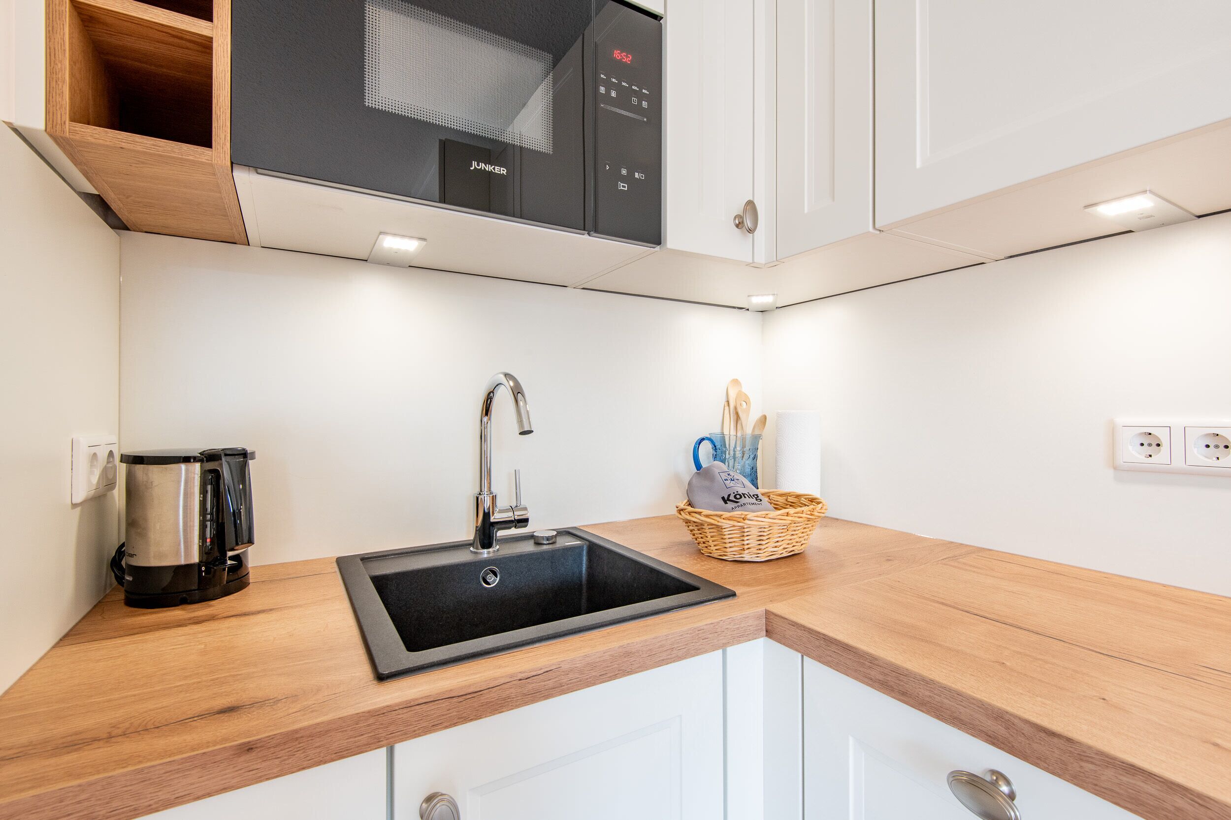A modern kitchen with a built-in dishwasher, a coffee maker, and a sink.