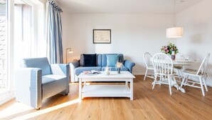 Ein modernes Wohnzimmer mit Sofa, Sessel, Couchtisch und Esstisch.