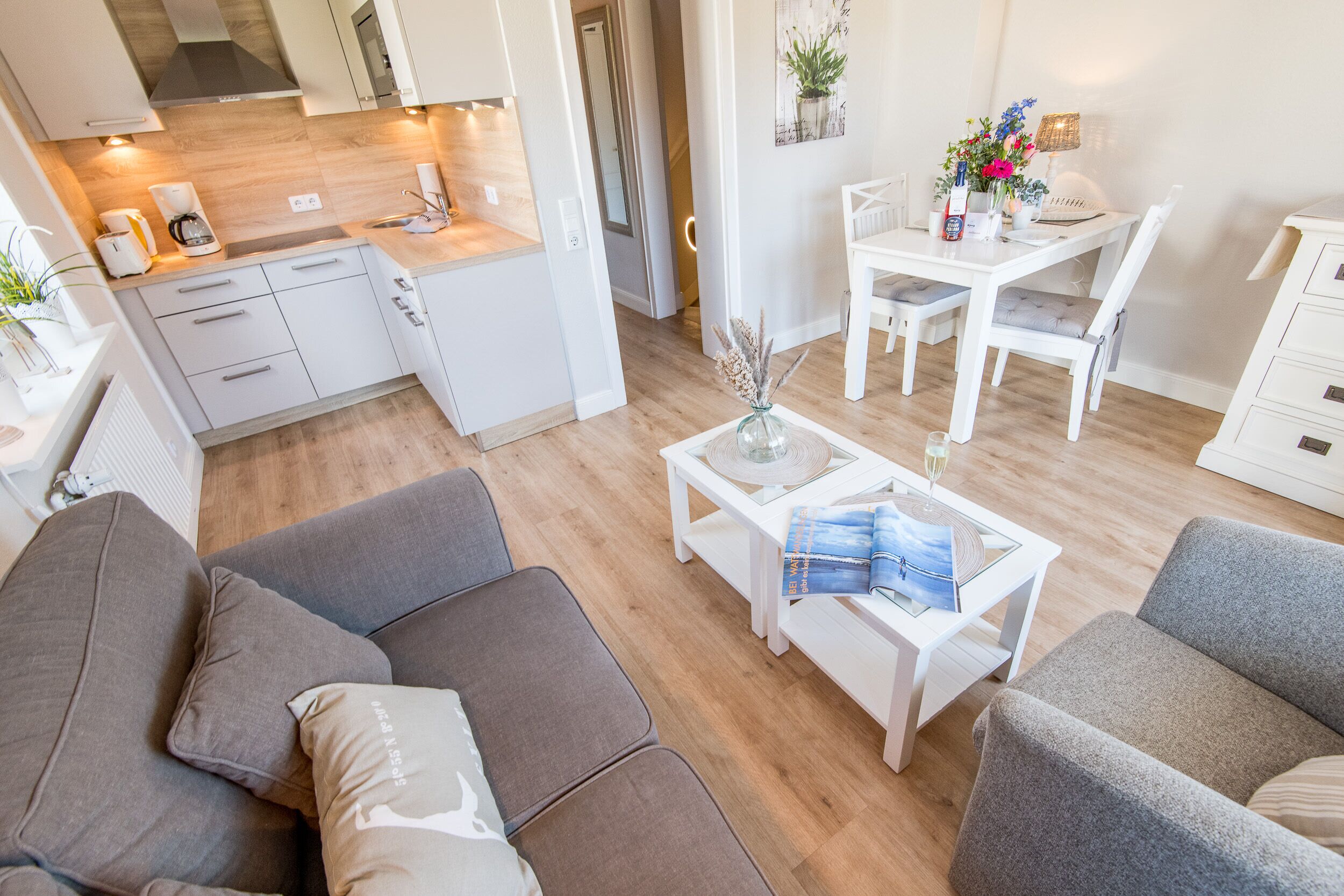 A modern living room with a sofa, a coffee table with magazines, and a dining area with a table and chairs.