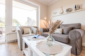 A modern living room with a sofa, a coffee table, and a vase with dried flowers.