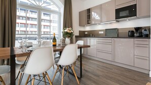 A modern kitchen with a dining area, large windows, and a view of buildings. - Ausblick. Komfortabel. Südbalkon (Westerland)