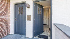 A double door entrance with a plaque, a small outdoor area with a tiled floor, and a white brick wall. - Sonnenfreisitz. Geschmackvoll. Exklusiv (Westerland)