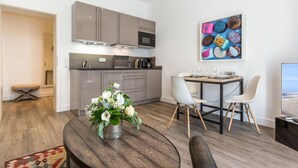 A modern kitchen with grey cabinets, a dining area with a table and chairs, and a decorative wall art piece. - Art your Life - Residence, Whg. 8 Tom (Westerland)
