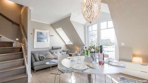 Ein modernes Wohnzimmer mit Essbereich, Treppe und großen Fenstern.