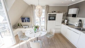 Eine moderne Küche mit weißen Schränken, einem eingebauten Backofen und einem Essbereich mit einem runden Tisch und vier Stühlen.