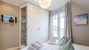 Ein Hotelzimmer mit einem Bett, einem an der Wand befestigten Fernseher, einem Kleiderschrank und einem Fenster mit Vorhängen.