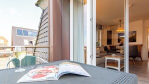 A balcony with a table, a glass of wine, and a magazine. - Zentral. Strandnah. Gemütlich. Haus Hauke, Whg. 8 Objekt-id: Hh/08 (Westerland)
