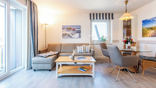 A modern living room with a sofa, coffee table, and dining area. - Zentral. Strandnah. Gemütlich. Haus Hauke, Whg. 8 Objekt-id: Hh/08 (Westerland)
