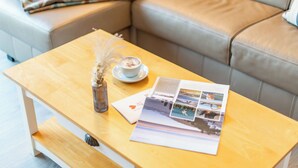A wooden table with a cup of coffee, a vase with dried flowers, and a booklet with photos. - Zentral. Strandnah. Gemütlich. Haus Hauke, Whg. 8 Objekt-id: Hh/08 (Westerland)