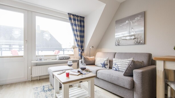 Ein modernes Wohnzimmer mit einem grauen Sofa, einem weißen Couchtisch und einem großen Fenster mit Meerblick.