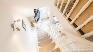 Eine Treppe mit weißen Spindeln, einem an der Wand befestigten Fernseher und einem gerahmten Bild.