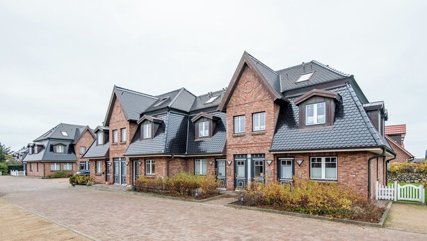 A row of brick houses with pitched roofs and multiple windows. - Exklusiv. Modern. Zentral. Haus Nordmarkgarten, Whg. 7a Objekt-id: Hng/07a (Westerland)
