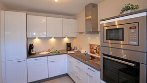 A modern kitchen with white cabinets, stainless steel appliances, and under-cabinet lighting. - Exklusiv. Modern. Zentral. Haus Nordmarkgarten, Whg. 7a Objekt-id: Hng/07a (Westerland)