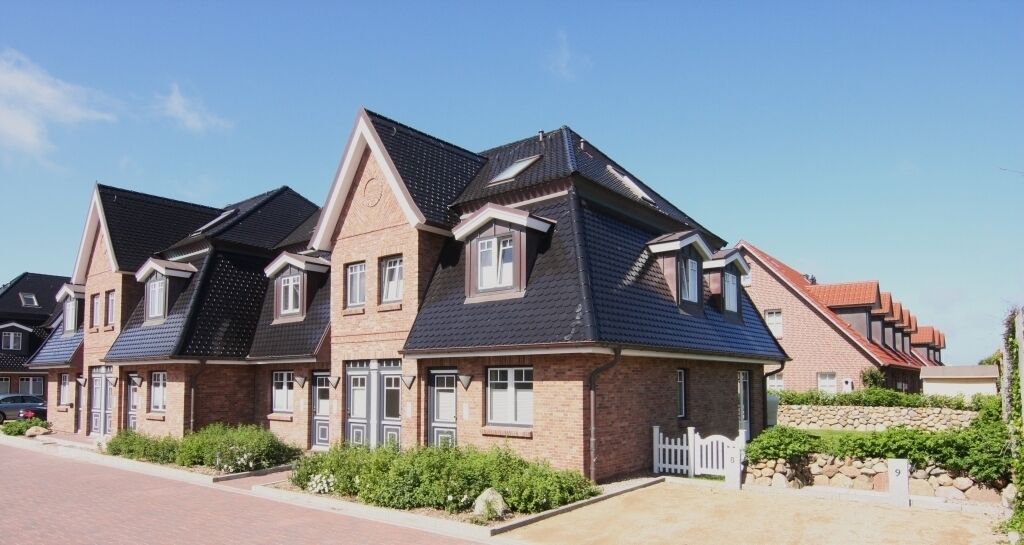 A row of modern houses with pitched roofs and brick exteriors.