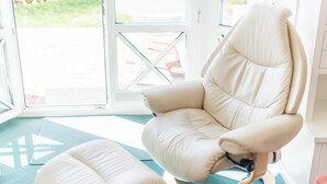 A beige reclining chair with a wooden base, positioned near a glass door with a view of an outdoor area. - Komfortabel. Strandnah. Zentral. Objekt-id: Has/09 (Westerland)