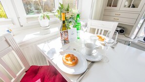 A dining table with plates of food, a bottle of wine, and a vase of flowers. - Komfortabel. Strandnah. Zentral. Objekt-id: Has/09 (Westerland)