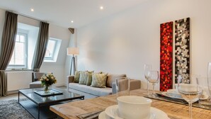 A modern living room with a sofa, coffee table, and dining table set for a meal. - Sauna. Exquisit. Stimmig (Westerland)