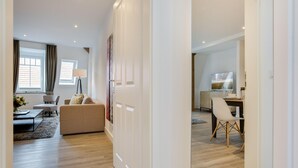 A modern living room with a sofa, a dining table, and a kitchen area visible through an open door. - Sauna. Exquisit. Stimmig (Westerland)