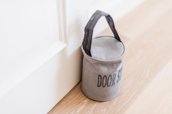 A gray doorstop with the text "DOOR STOP" placed on a wooden floor near a white door. - Modern. Lichtdurchflutet. Wellness (Westerland)