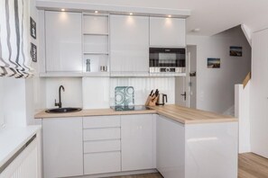 Una cocina moderna con armarios blancos, encimera de madera y horno empotrado.