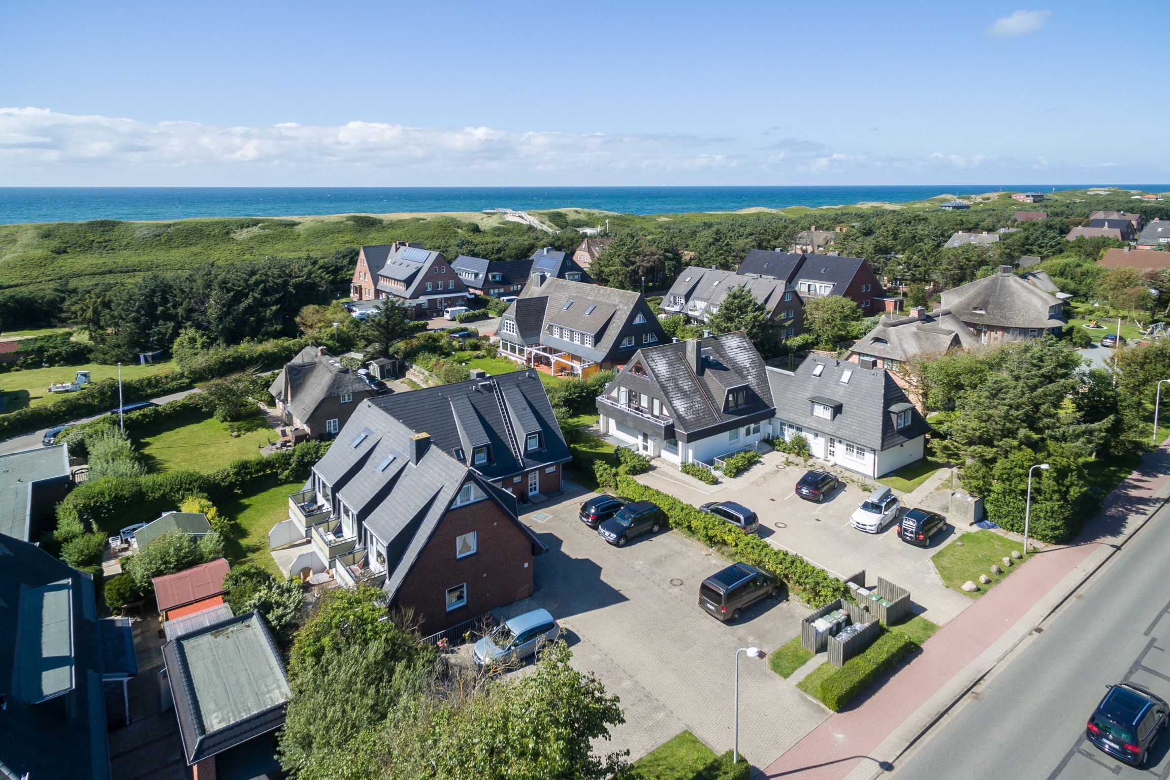 An aerial view of a residential area with houses, a parking lot, and a road.