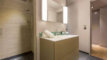Ein modernes Badezimmer mit Dusche, Waschbecken, Handtuch und Spiegel.