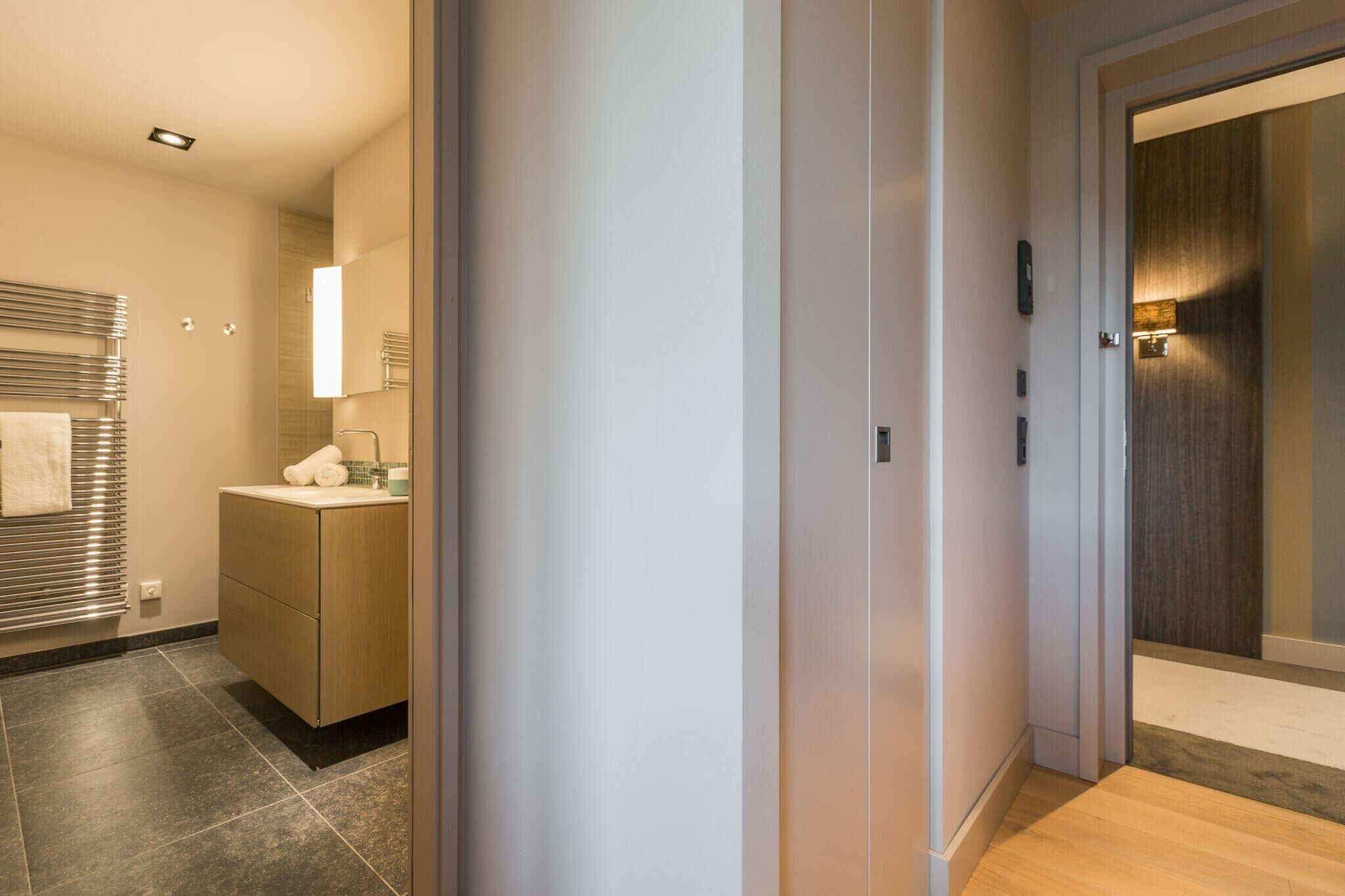 A modern bathroom with a shower, a toilet, and a sink. There is a towel rack and a mirror above the sink.
