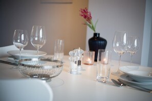 Una mesa dispuesta con copas de vino, platos, un bol de cristal y saleros y pimenteros.
