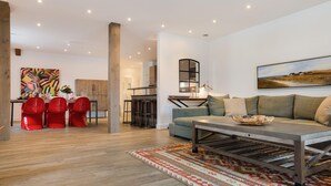 A modern living room with a sofa, coffee table, and red chairs. There is a painting on the wall and a rug on the floor. - Großzügig. Ausblick. Wellness (Westerland)