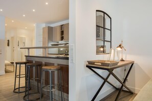 A modern kitchen with a bar area, stools, and a unique wall-mounted table with a lamp.