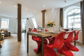 A dining area with a wooden table, red chairs, and a vase of flowers.