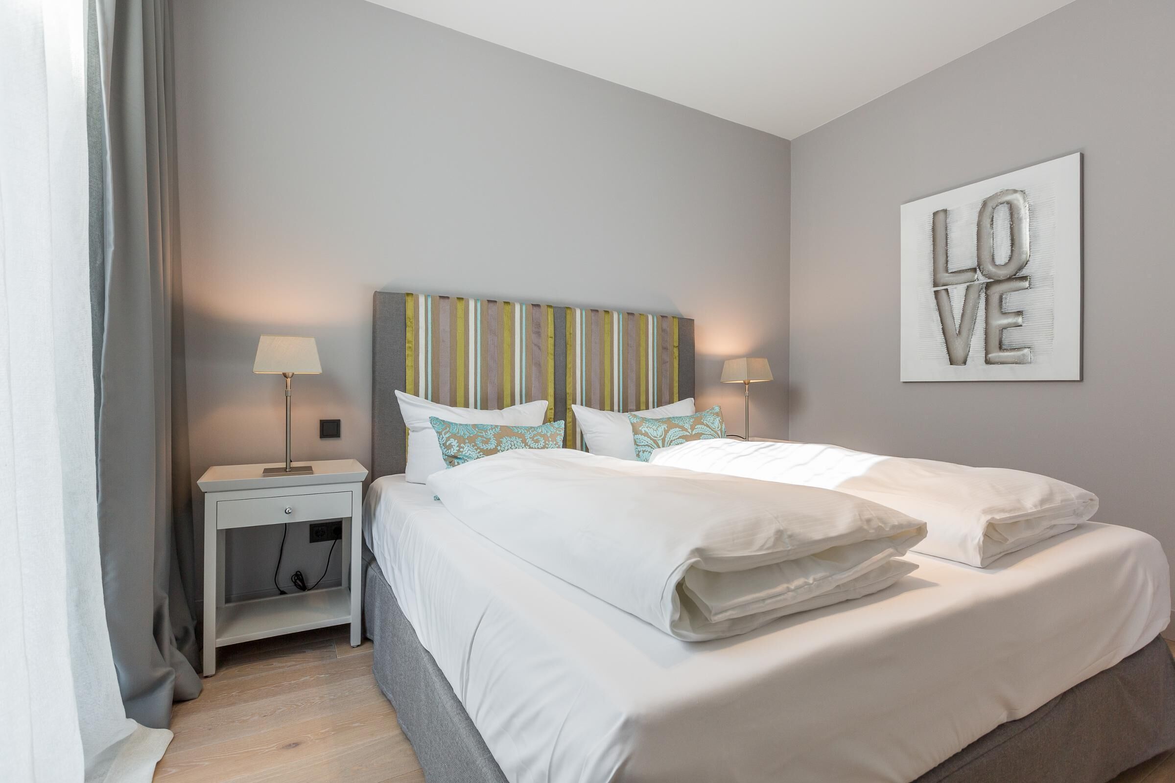 A neatly arranged bedroom with a bed, two bedside tables, and a wall-mounted artwork.