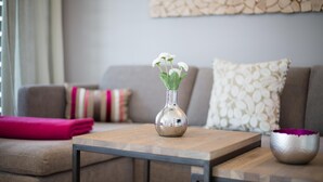 A modern living room with a sofa, a coffee table, and decorative items including a vase with flowers and a metallic bowl.