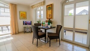 A dining area with a table, chairs, a TV, and artwork.