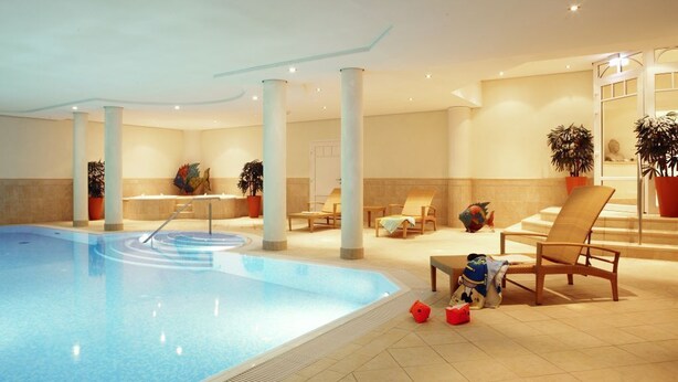 A swimming pool with lounge chairs and potted plants.
