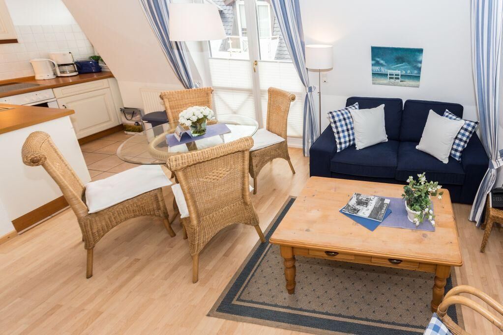 En hyggelig stue med fletningsmøbler, en mørkeblå sofa og et træbord.