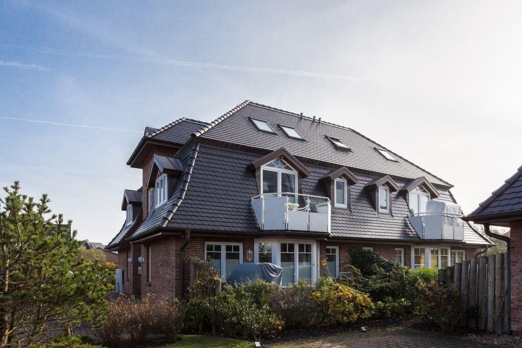 A two-story house with a sloped roof, dormer windows, and a covered outdoor area.