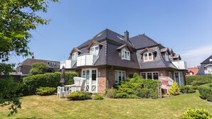 A two-story house with a dark roof, brick exterior, and a well-maintained lawn.