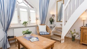 A cozy room with a wooden table, wicker chair, and a staircase.