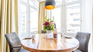 Une table ronde en bois, avec une bouteille de vin, un vase de fleurs et deux chaises.