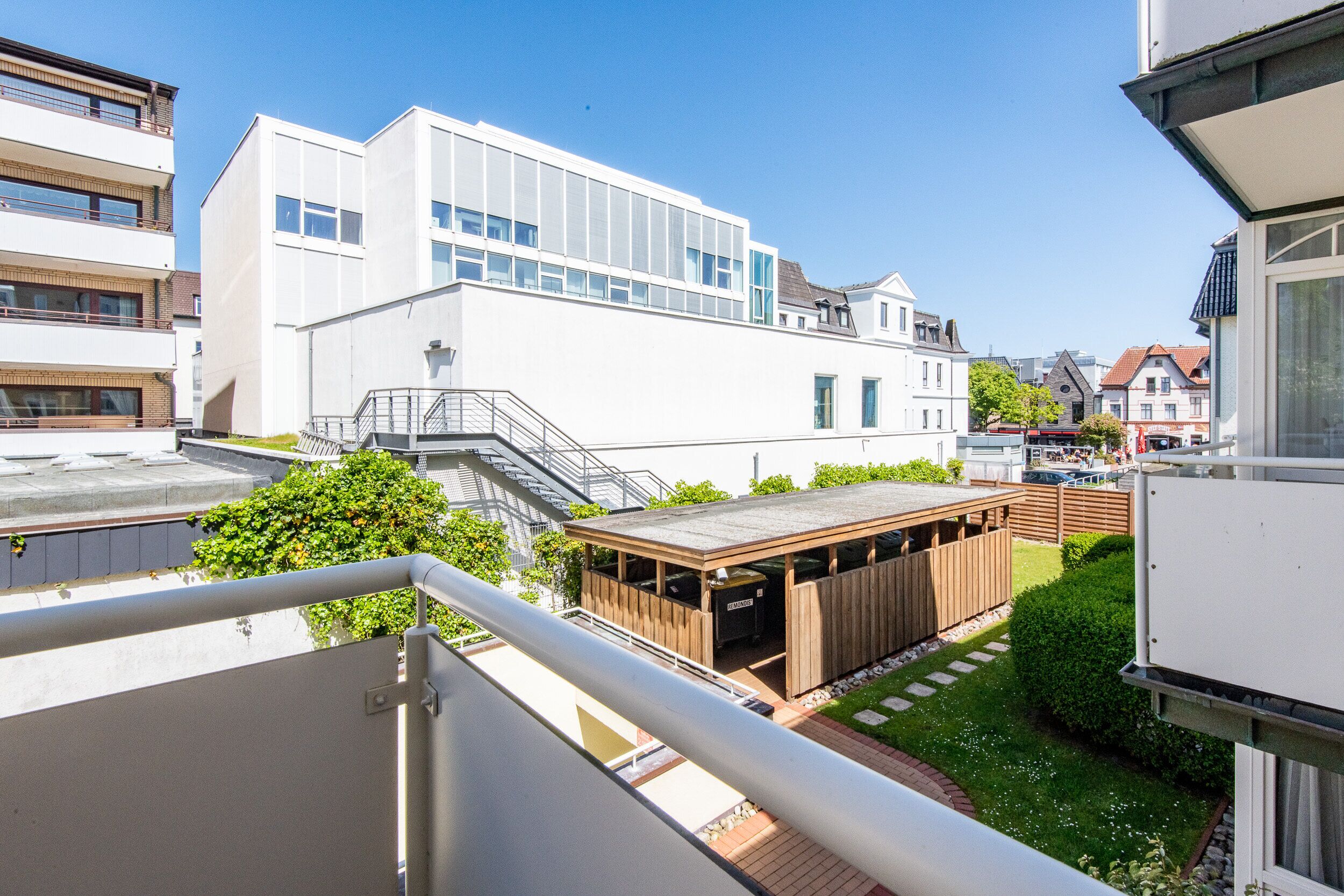 A modern building with a flat roof, large windows, and a covered outdoor area with a barbecue.