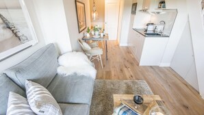 Una sala de estar moderna con un sofá gris, una mesa de centro y un comedor con una mesa pequeña y sillas.