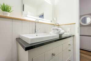A modern bathroom with a white sink, black countertop, and a mirror above it.