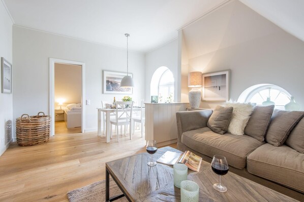 A modern living room with a wooden coffee table, a sofa, and a dining area with a table and chairs.