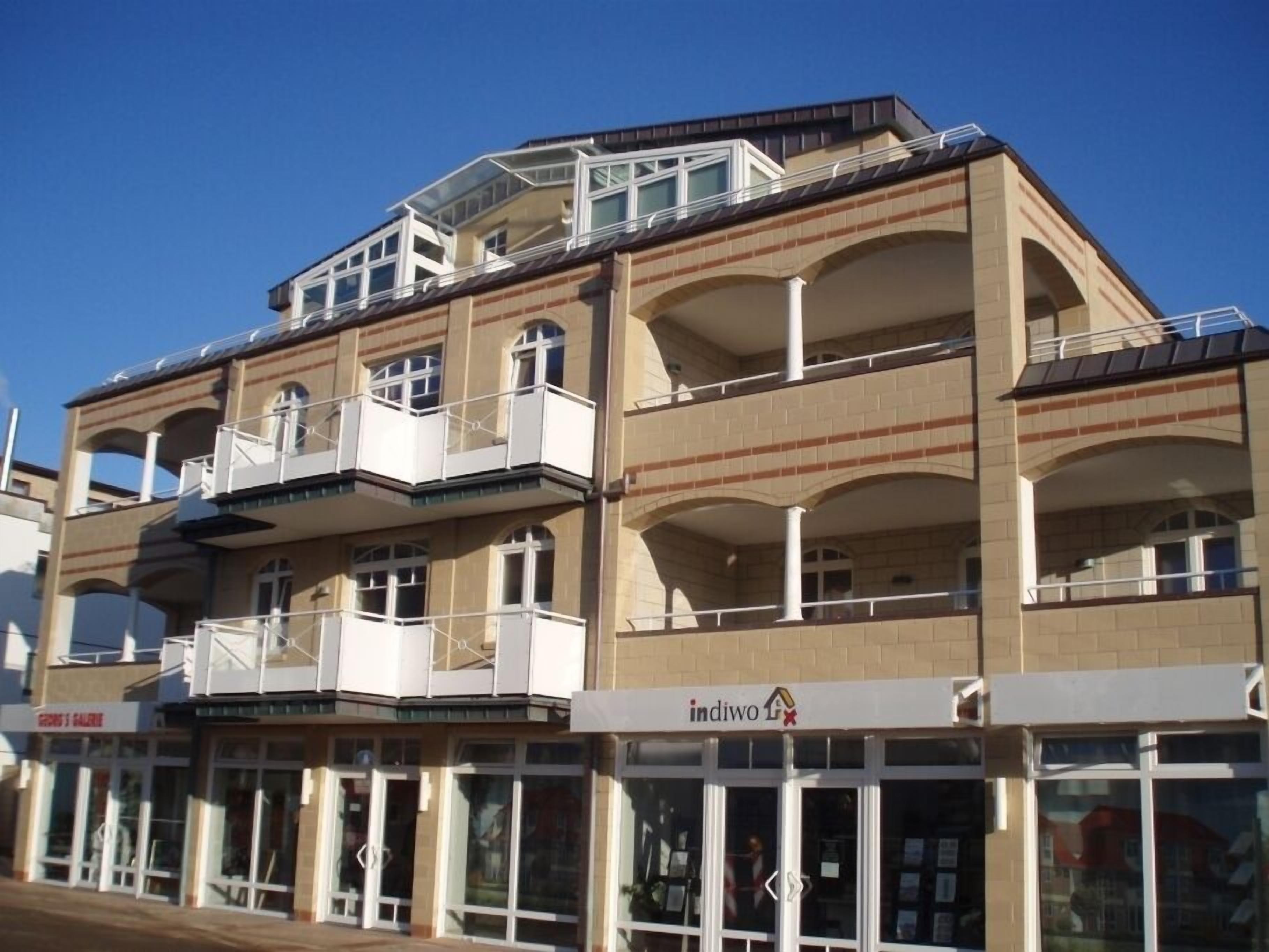 A multi-story building with balconies, a storefront, and a sign that reads "indivo".