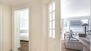 Un salon moderne avec un canapé, un pouf et un coin repas agrémenté d’un plateau.