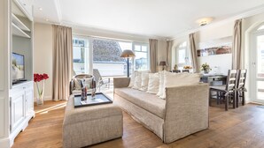 Un salon spacieux comprenant un canapé, un pouf et un coin repas.